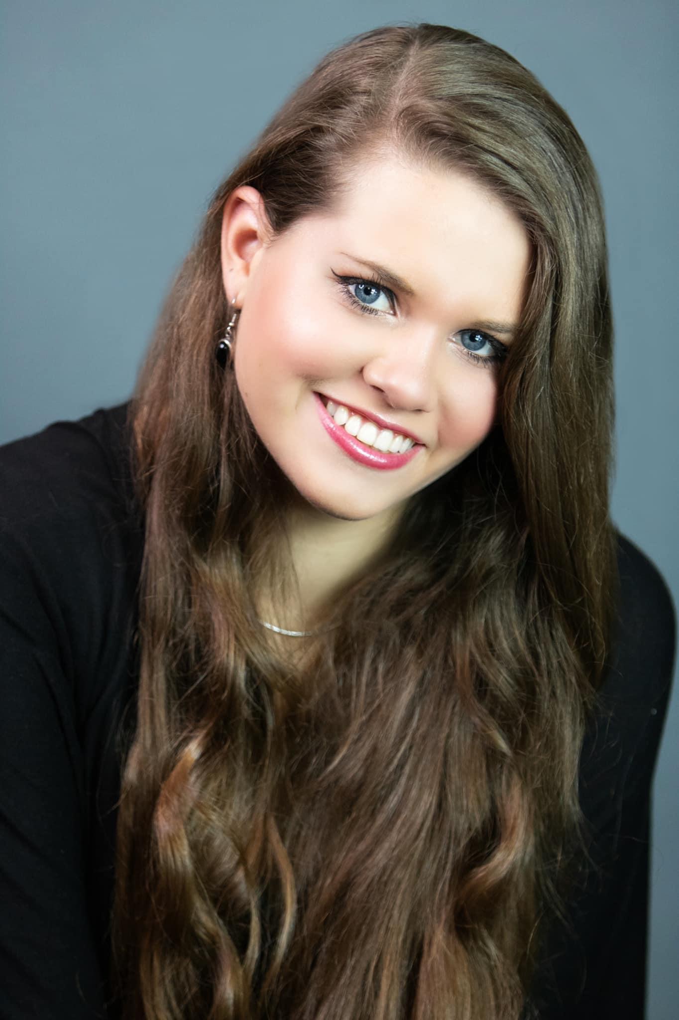 Kendall Morgan Lacy smiling against a blue-gray backdrop